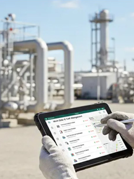 Technikus tableten vezeti a munkalistát egy ipari csővezeték-létesítményben